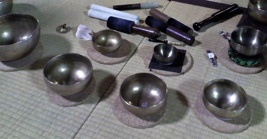 Varios cuencos tibetanos de metal sobre un tapete, listos para una sesión de sonido.