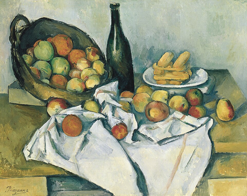 Bodegón de una cesta de manzanas volcada sobre una mesa con un mantel blanco, una botella y un plato de panecillos.