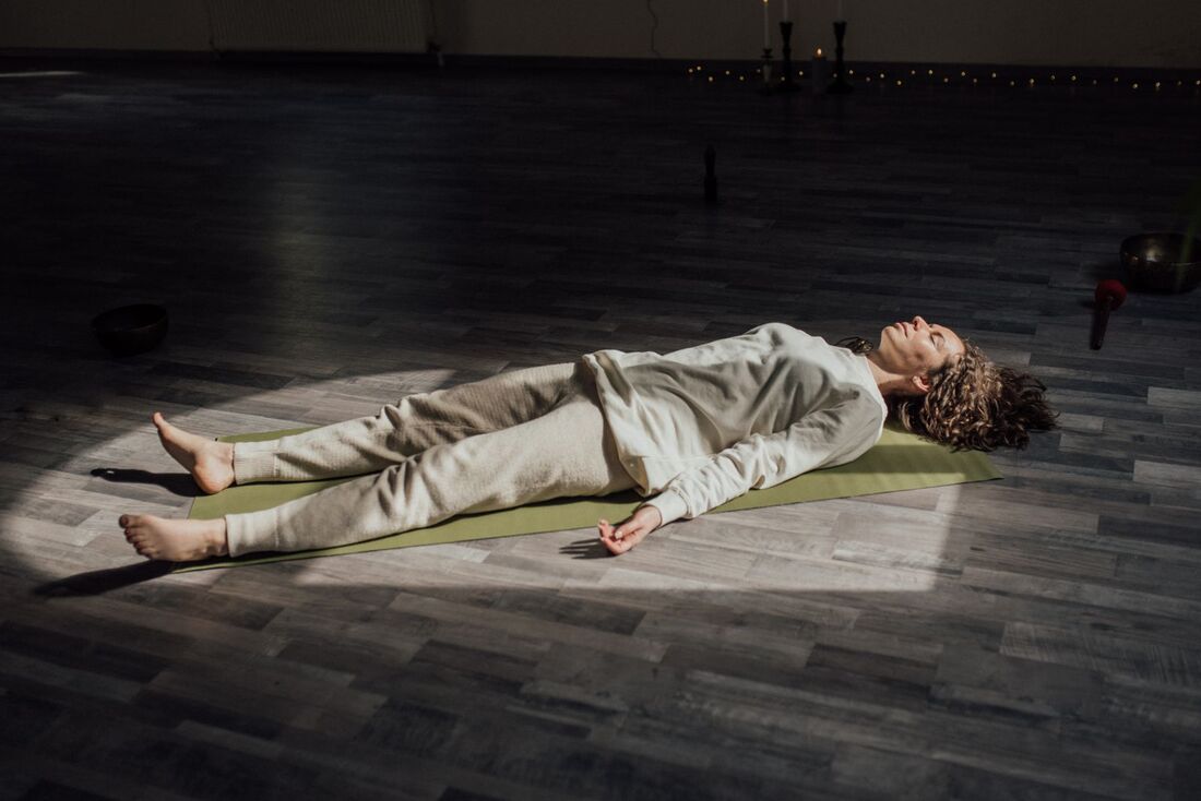 Una persona en savasana sobre su tapete, completamente quieta, al final de la práctica.